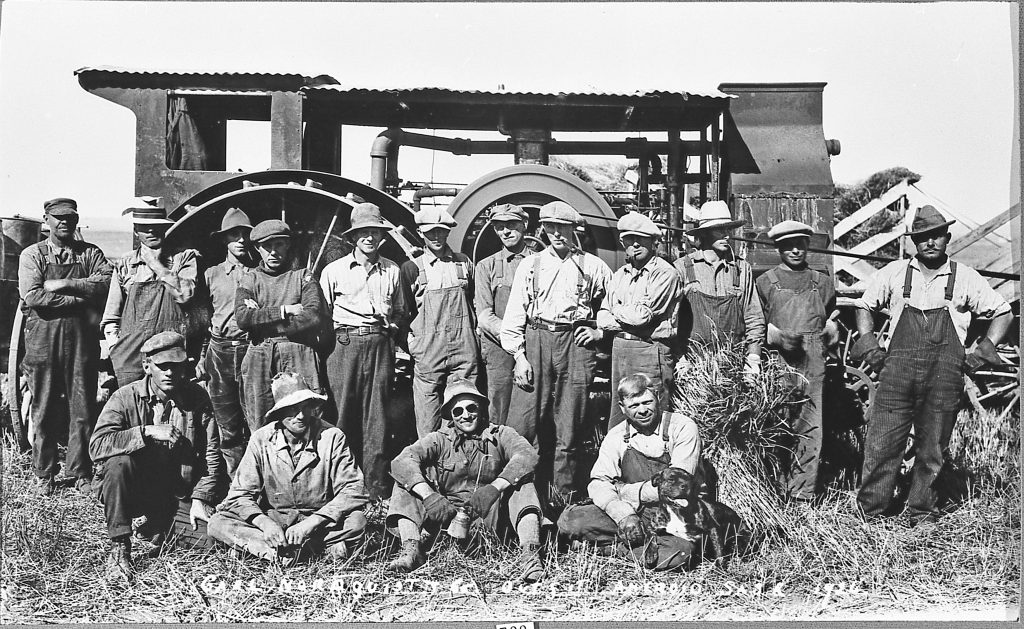 Foto av en gruppe menn foran traktor