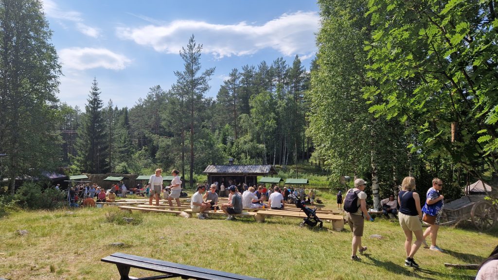 Foto av flere mennesker i et amfi i en grønn skog.