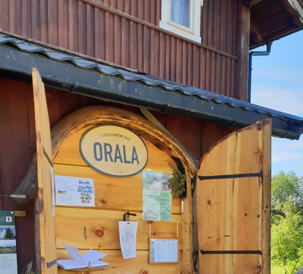 Foto av en informasjonstavle med et skilt med teksten "I svedjerøktens rike - Orala"
