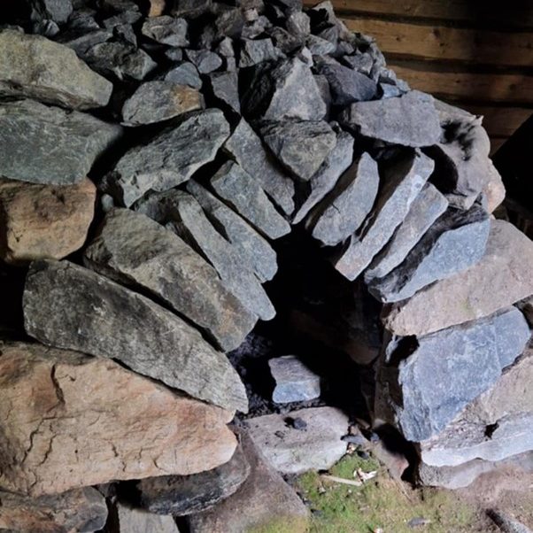 Foto av en eldre ovn bygget av mange steiner.