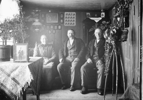 Norske utvandrere i egen stue Minnesota ca. 1910-1915. Svart-hvittfoto av tre voksne i en stue
