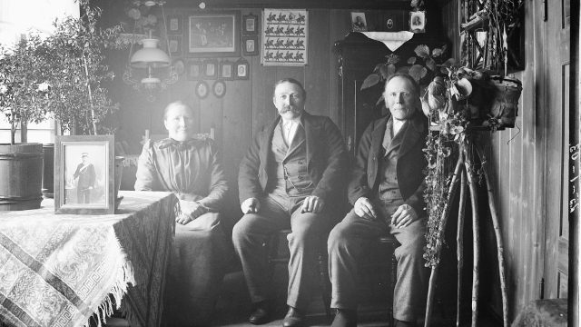 Norske utvandrere i egen stue Minnesota ca. 1910-1915. Svart-hvittfoto av tre voksne i en stue