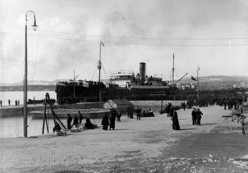 Passasjerskipet Manchester Shipper 8. april i 1902. 764 passasjerer reiste fra Kristiania. 503 av passasjerene hadde arbeidskontrakt med et kanadisk selskap. Svart-hvittfoto av et stort passasjerskip ved en havn, med en stor folkemengde på havna.