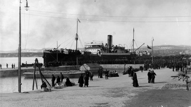 Passasjerskipet Manchester Shipper 8. april i 1902. 764 passasjerer reiste fra Kristiania. 503 av passasjerene hadde arbeidskontrakt med et kanadisk selskap. Svart-hvittfoto av et stort passasjerskip ved en havn, med en stor folkemengde på havna.