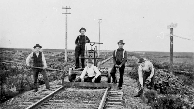 Eksempel fra USA: Rallargjeng, fotografert mellom 1890 og 1935. Svart-hvittfoto av fem menn med dresin og arbeidsverktøy på en togskinnegang